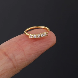 Detailed macro of gold-plated nose ring with five white cubic zirconia stones shown on finger