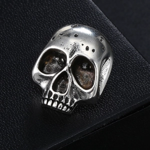 Macro shot of vintage skull brooch with oxidized silver finish on black leather background