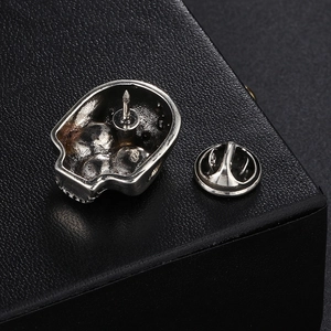 Vintage silver skull brooch for biker jackets with butterfly clasp on leather background