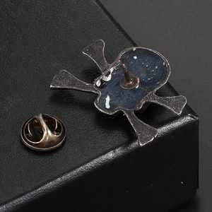 Detailed back view of vintage silver skull brooch showing the pin and butterfly clasp