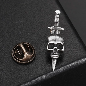 Macro shot of gothic skull and dagger brooch in vintage silver finish on black display