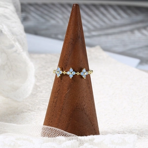 Gold plated ring featuring three light blue flower petals on a wooden cone display stand