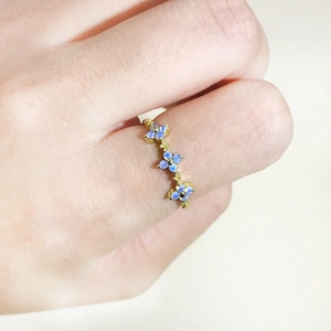 Elegant gold plated ring with blue flower zircon details on a woman's hand