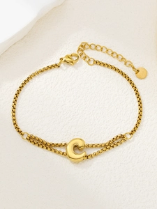 Detail van een vergulde roestvrijstalen dubbele schakelarmband met hanger in de vorm van letter C