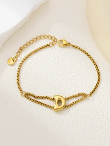 Detail van een vergulde roestvrijstalen armband met een gepolijste letter D hanger