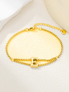 Detailopname van vergulde roestvrijstalen armband met letter E hanger en S.Steel-tag