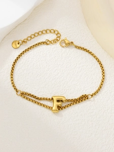 Detail van de vergulde roestvrijstalen schakelarmband met de letter F hanger en sluiting