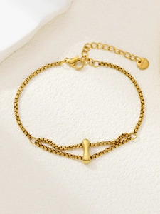 Detail van een gouden roestvrijstalen armband met een bedeltje in de vorm van een halter