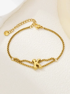 Detail van gouden roestvrijstalen armband met letter K-hanger en een stevige karabijnsluiting