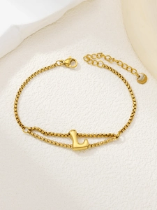 Detail van een dubbellaagse vergulde armband met een gepolijste hanger van de letter L