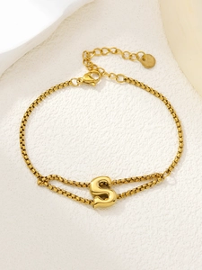 Detailweergave van een vergulde dubbellaagse armband met een 3D letter S hanger