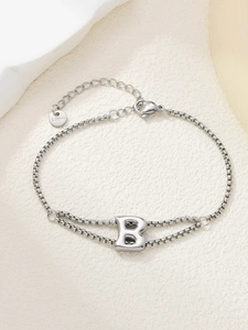 Macro-opname van de zilveren roestvrijstalen dubbele armband met de letter B-hanger
