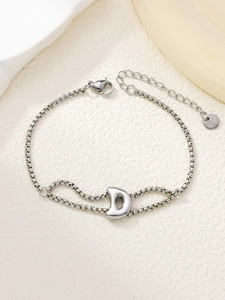 Detail van een zilveren roestvrijstalen armband met een gepolijste letter D hanger