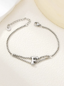 Macro-detail van een zilveren dubbellaagse roestvrijstalen armband met een letter F hanger