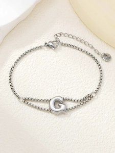 Detailweergave van de zilveren dubbele roestvrijstalen armband met een letter G hanger