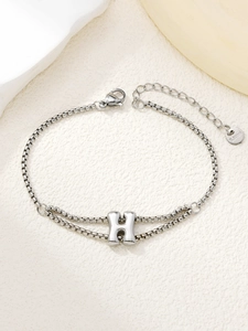 Detail van zilveren roestvrijstalen dubbellaagse armband met een H-vormige hanger
