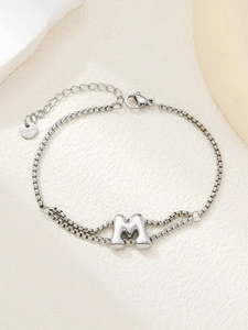 Gedetailleerde close-up van een zilveren roestvrijstalen armband met 3D-letter M bedel