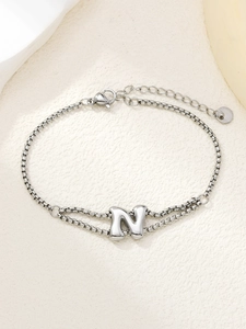 Macro detail van de zilveren roestvrijstalen schakelarmband met een 3D gepofte letter N hanger