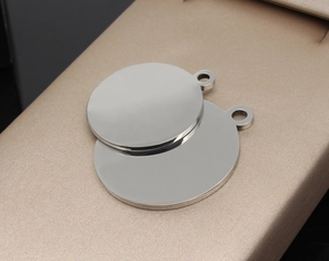 Polished circular stainless steel pet ID tags with mirrored surface on a champagne stand