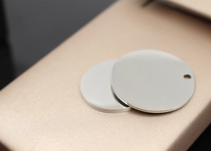 Macro shot of two round polished stainless steel pet tags on a textured display base