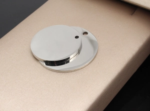 Polished stainless steel round pet ID tag with hole on a premium champagne gift box background