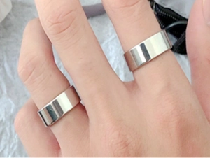 Close-up of minimalist silver titanium steel wide band rings with mirror finish for men and women