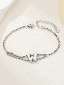 Macro-detail van de zilveren roestvrijstalen schakelarmband met letter W-bedeltje en karabijnslot