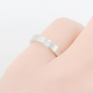 Macro shot of brushed stainless steel ring with a square-cut inlaid zircon crystal