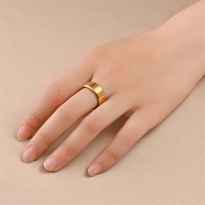 Nahaufnahme eines matten Titanrings in Gold mit gebürsteter Oberfläche auf einer Hand