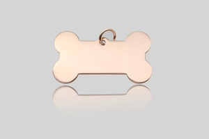 Close-up of a bone-shaped rose gold pet ID tag with smooth finish and metal split ring