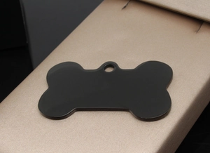 Macro detail of bone-shaped black matte stainless steel pet tag on premium display pad
