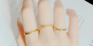 Close-up of three gold titanium rings featuring polished and frosted minimalist finishes