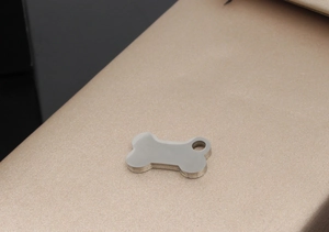 Close-up of bone-shaped stainless steel dog tag on champagne satin background