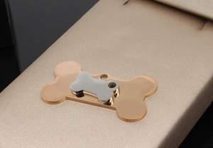 Macro shot of double-layered bone-shaped stainless steel pet ID tag with polished finish