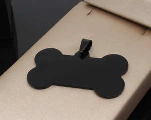 Polished black bone-shaped stainless steel pet ID tag on a premium textured display surface