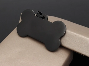 Macro detail of bone-shaped black stainless steel pet tag on a luxury silk jewelry box