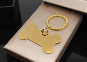 Detailed close-up of a gold bone-shaped stainless steel pet ID tag on champagne silk fabric