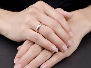 Gros plan d'une bague en acier titane poli or rose sur un doigt masculin