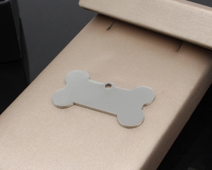 Macro view of a bone-shaped stainless steel pet ID tag with a polished silver finish