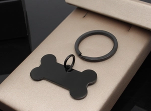 Close-up of black bone-shaped stainless steel pet ID tag on champagne gold display