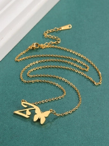 Detail of gold stainless steel butterfly and letter A pendant necklace with high-polish finish