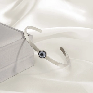 Detaillierte Nahaufnahme eines silbernen Evil Eye Armreifs auf Seidenhintergrund