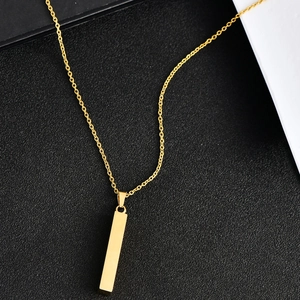 Macro detail of a polished gold rectangular pendant with a refined link chain