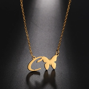 Close-up of golden letter C necklace with butterfly pendant on dark textured background
