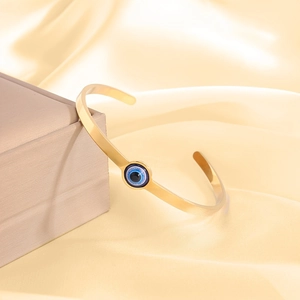 Verstellbares goldenes Evil Eye Manschettenarmband aus Edelstahl auf Champagner Seide