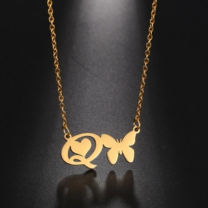 Macro shot of gold butterfly pendant with initial Q and hollow heart detail