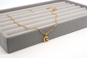 Nahaufnahme des polierten Gold-Anhängers Buchstabe G auf einer feinen Kette im Etui