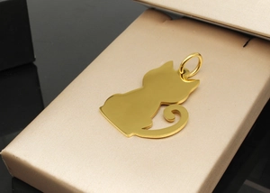 Detailed view of a gold-plated stainless steel cat silhouette pet ID tag on satin