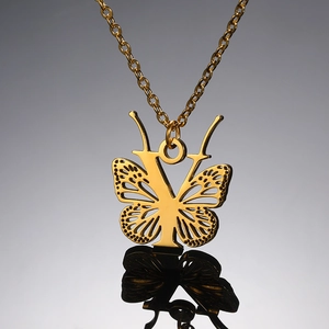 Macro detail van gouden vlinder hanger met letter V en verfijnde schakelketting