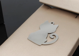 Close-up of a cat-shaped stainless steel pet ID tag with a polished mirror finish